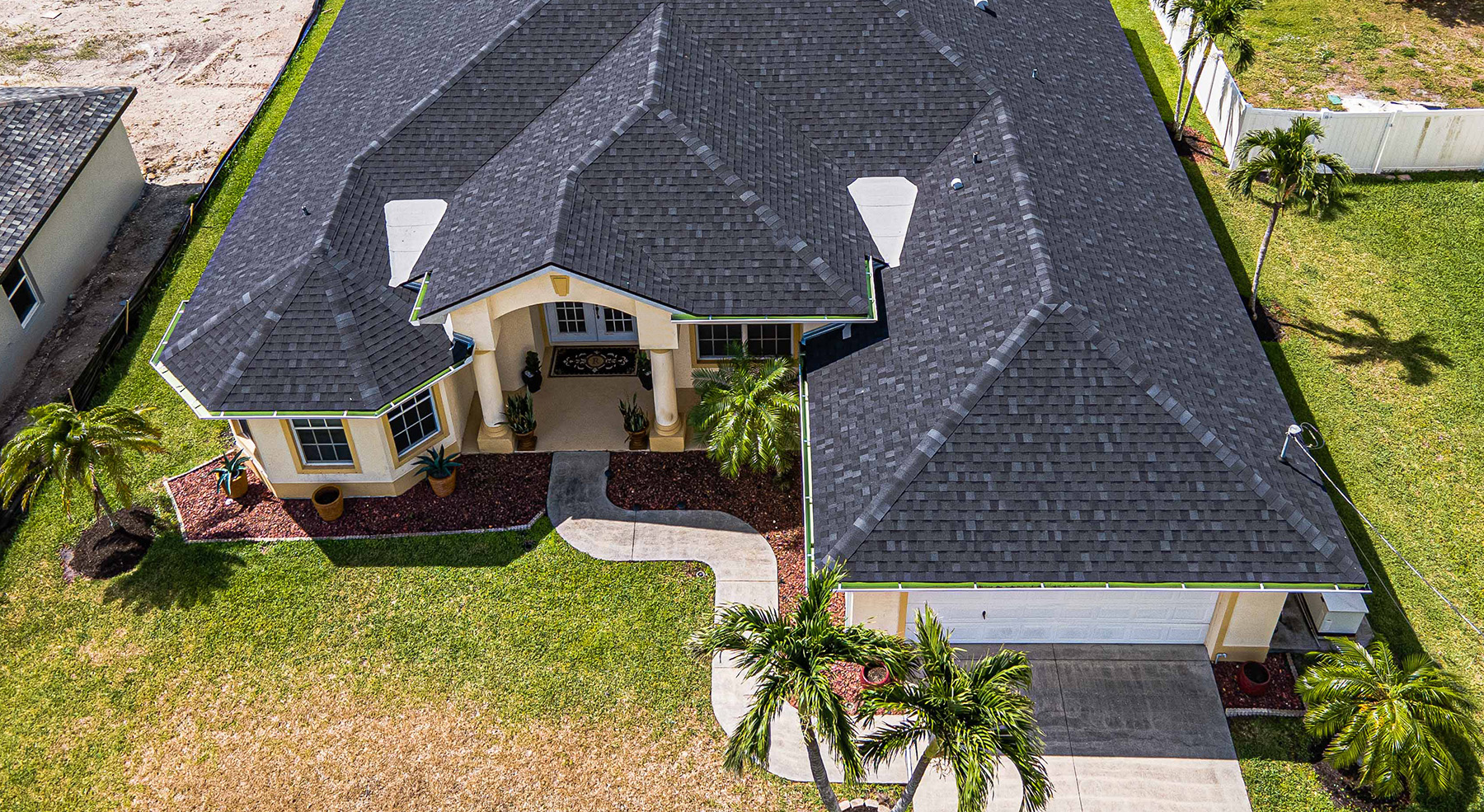 drone image of a residential single family home with dark gray asphlat shingle roof